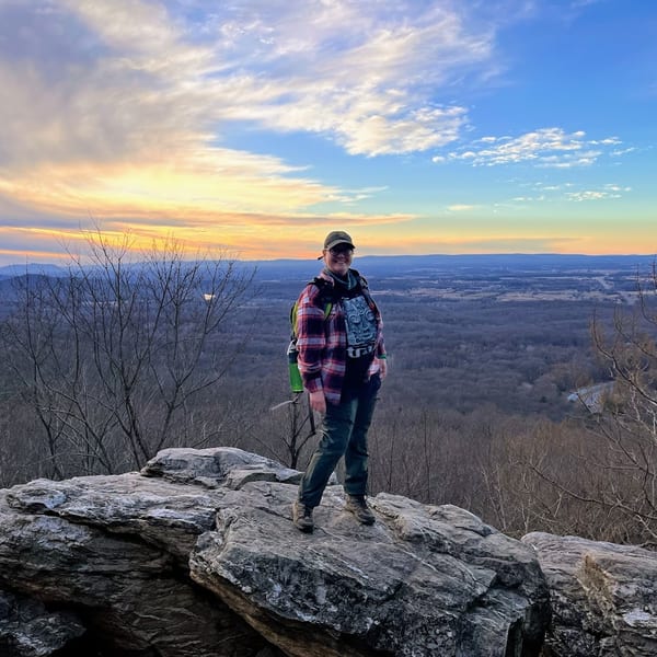 Woman hiking through a forest trail at sunset